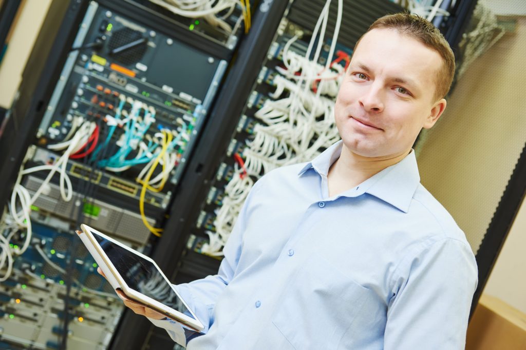 Networking service worker portrait. network engineer administrator with tablet computer checking server hardware equipment of data center